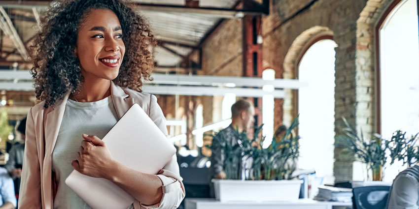Smiling young woman carrying laptop